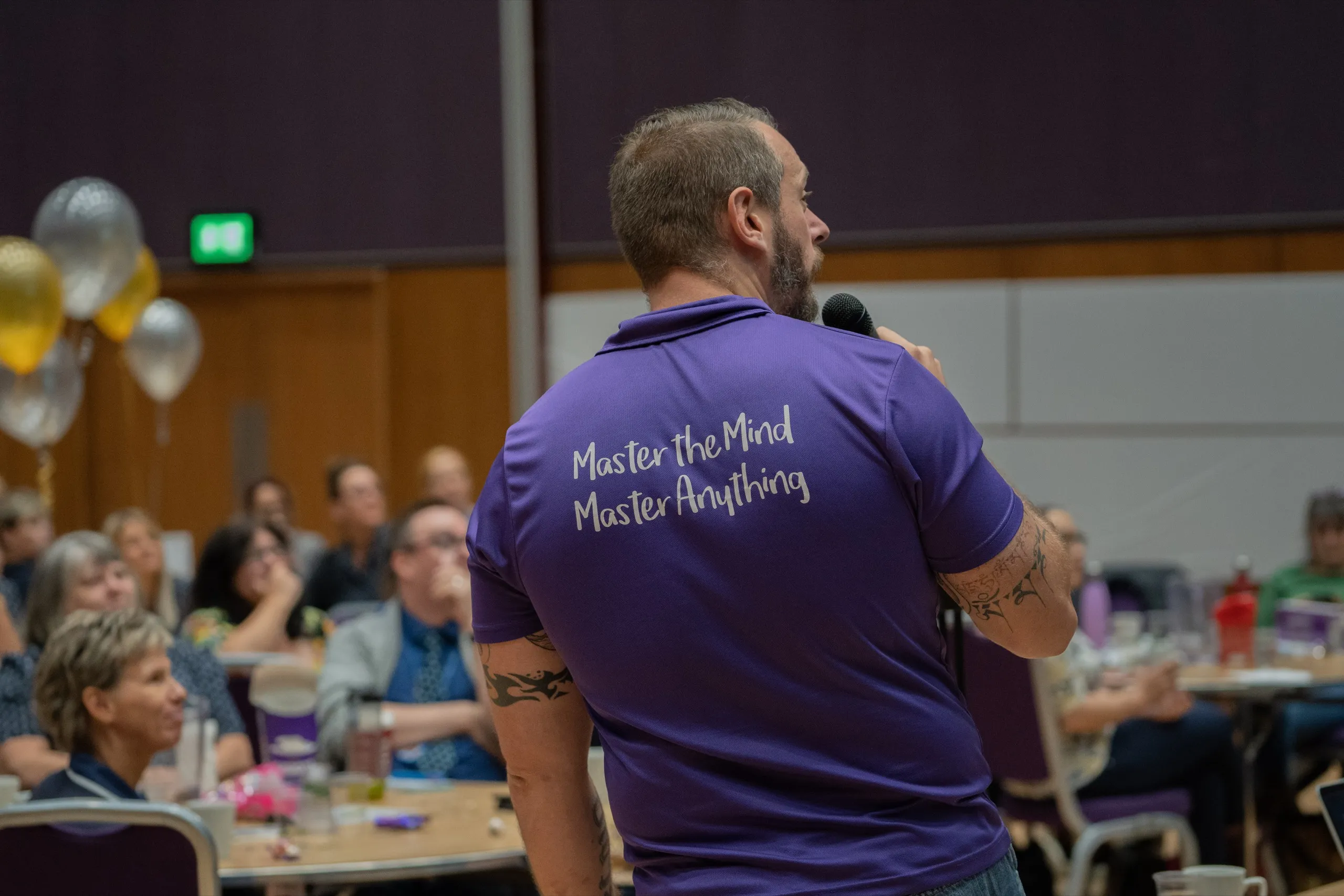 Dave Cottrell speaking into a microphone to a seated audience at a corporate event